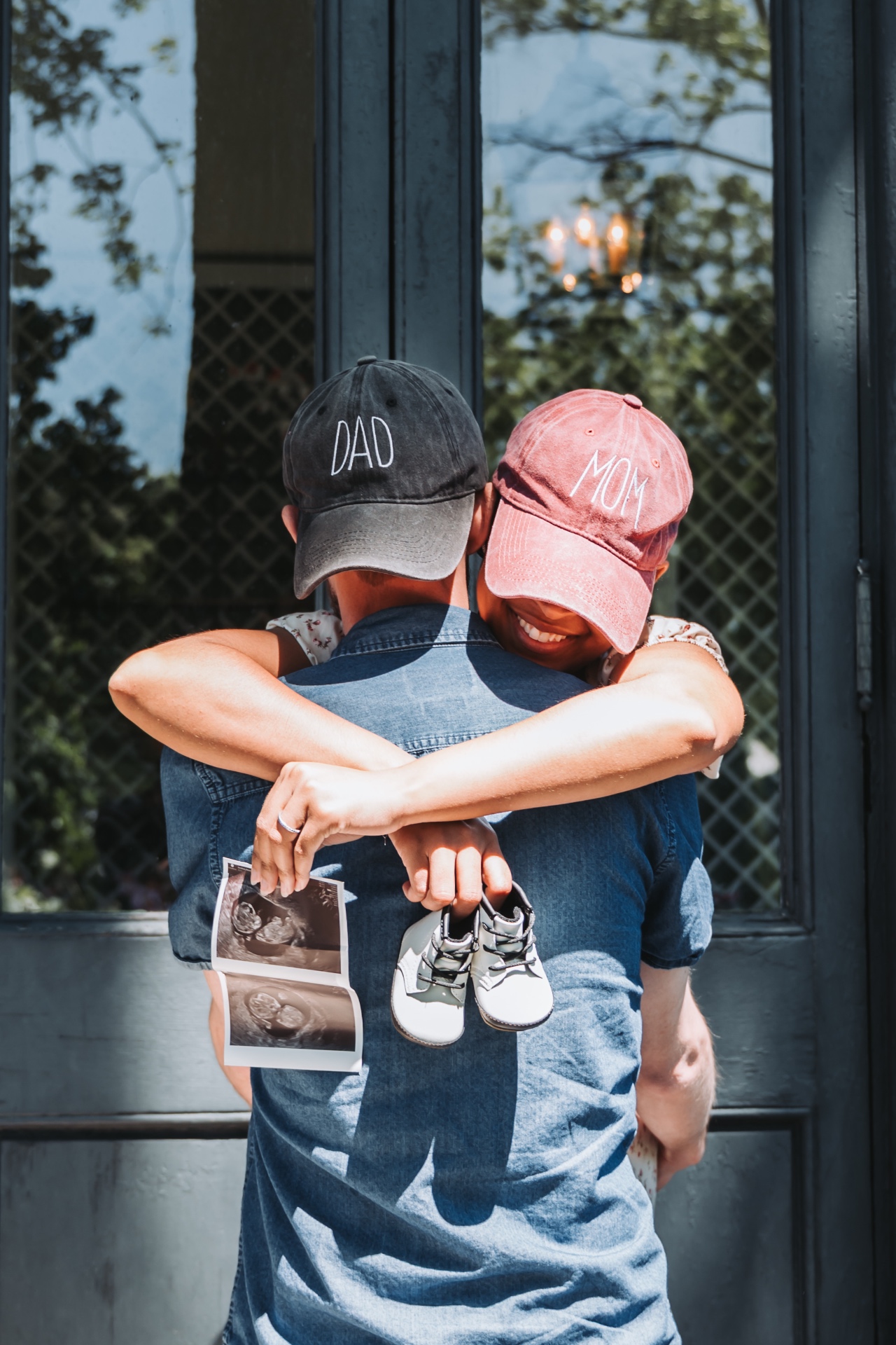 Mom & Dad hugging with sonogram and baby shoes